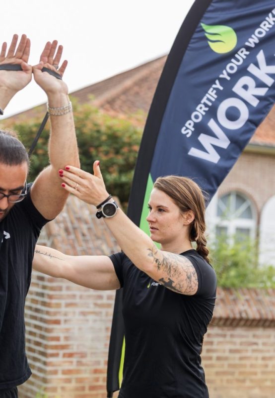 Vrouwelijke coach corrigeert de houding van een man tijdens een buitentraining met weerstandsband.