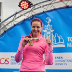 Vrouw in roze sportoutfit toont trots haar medaille na het behalen van een loopwedstrijd