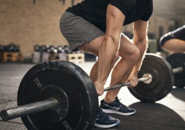Athlete preparing to lift a barbell during a strength training session in the gym.