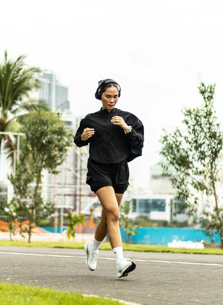 Athlete running outdoors wearing headphones during a solo training session.